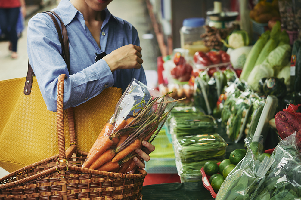 Shopper at a farmer's market selects organic carrots, embodying the clean label movement by choosing fresh and natural produce