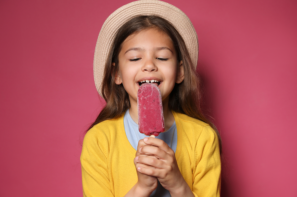 Smiling girl enjoying a natural food colouring popsicle, symbolizing healthier choices for children's treats