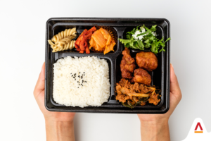 The same ready-made meal kit from Image 1, held by two hands, showcasing the convenience of on-the-go meals.